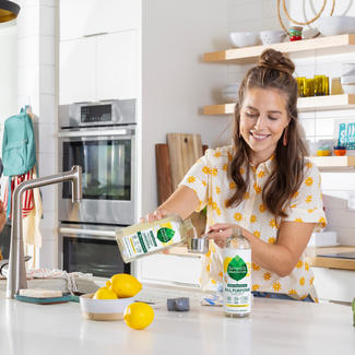 Family in kitchen, adult using cleaner concentrate, children interacting with each other